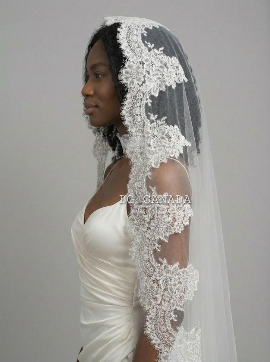 May include: A white bridal veil with detailed floral lace edging. The veil is worn over a white satin wedding dress. The image includes the text "BG CANADA".